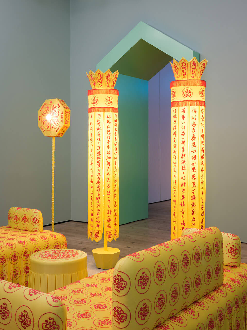 Immersive yellow installation with Chinese calligraphy banners, decorated furniture, and traditional patterns in gallery space