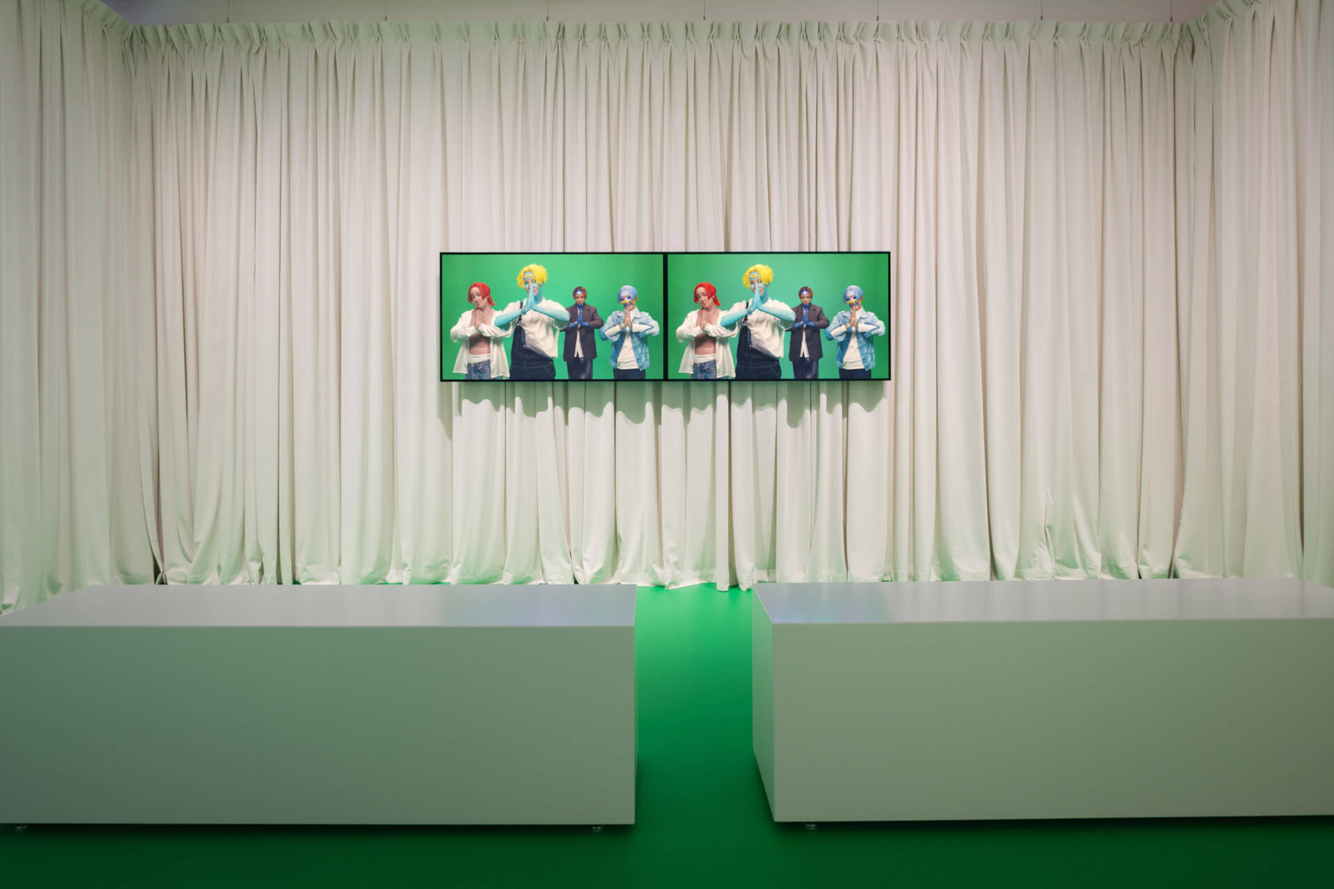 Gallery visitor watching Sin Wai Kin's "It's Always You 2" large screen video installation with green sculptural elements and white curtains