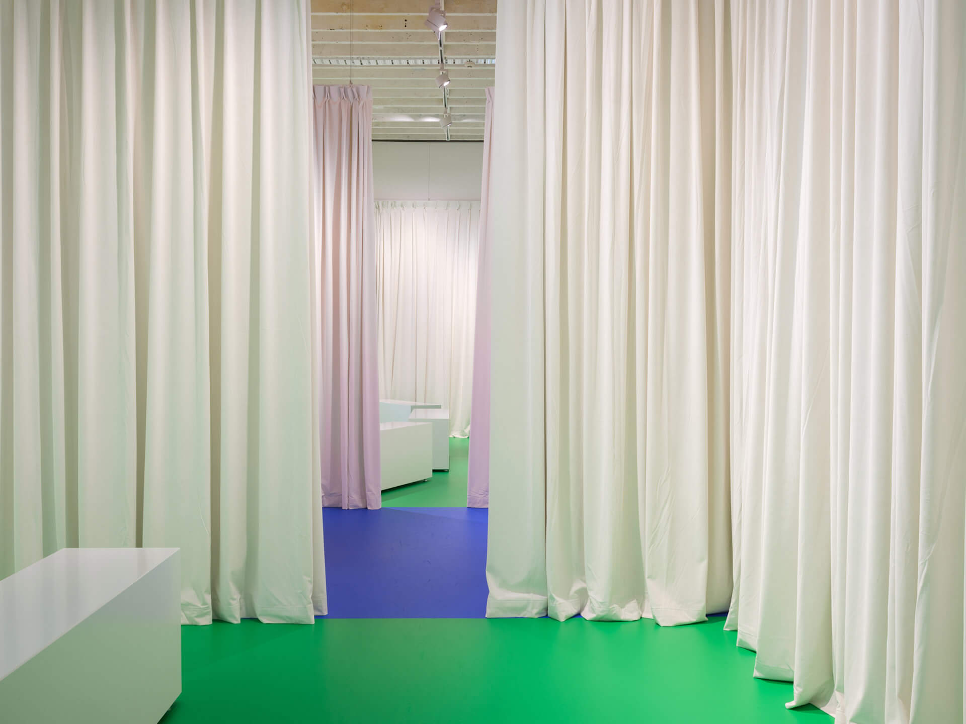 White Rabbit Gallery ground floor with white curtain dividers and green flooring during Tender Comrade exhibition