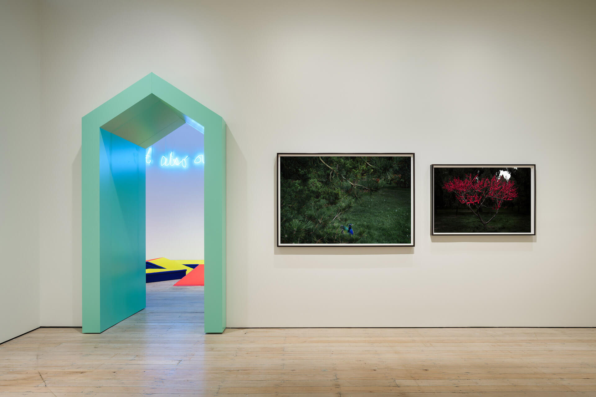 Gallery Level 2 with mint green archway, neon sign, and framed photography works displayed on white walls