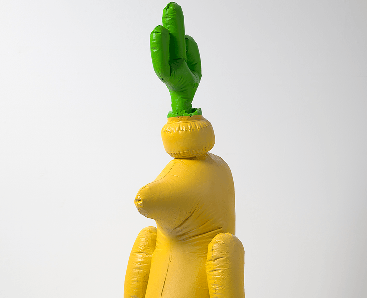 A fibreglass sculpture that looks like a blow up balloon cactus on a yellow figure.