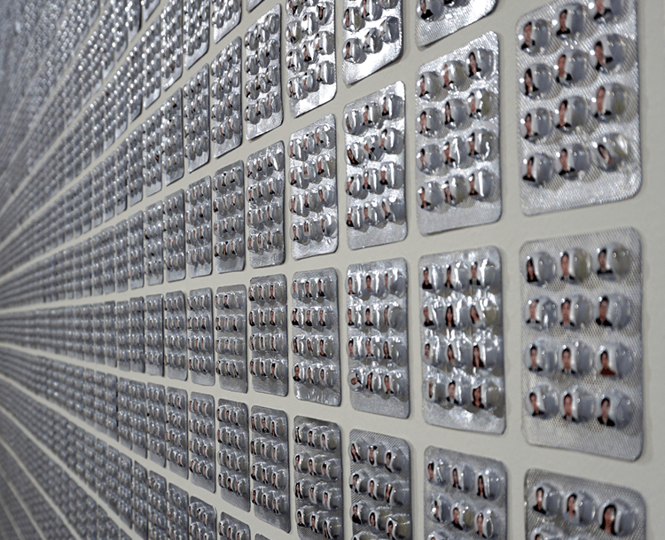 An installation of old blister packs with each blister filled with a portrait